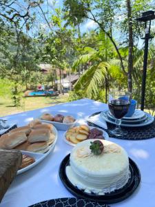 a table with plates of bread and a cake and a glass of wine at Sítio do Vô Pisco in Camboriú