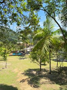 park z drzewami i dom w tle w obiekcie Sítio do Vô Pisco w mieście Camboriú