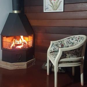 a chair in front of a fireplace with a fire at Chalés Alto do Capivari in Campos do Jordão