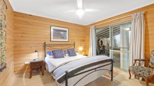a bedroom with a bed and a chair and a window at Villa Pandanus - Patonga Beach in Patonga Beach