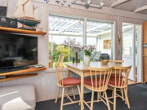 a dining room with a table and chairs and a tv at Holiday home Aabenraa LXX in Aabenraa