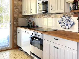 uma cozinha com armários brancos e um forno com placa de fogão em Holiday home GUSUM II em Gusum