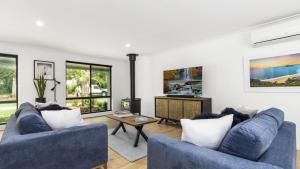 uma sala de estar com dois sofás azuis e uma televisão em Jewellers Retreat - Pearl Beach em Pearl Beach