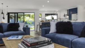 a living room with two blue couches and a table at Jewellers Retreat - Pearl Beach in Pearl Beach