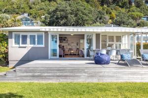 a house with a blue bag sitting on a deck at Bach on the Beach - Coast & Country in Onetangi