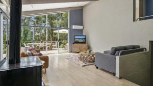 sala de estar con sofá y chimenea en Melaleuca Lodge - Pearl Beach, en Pearl Beach