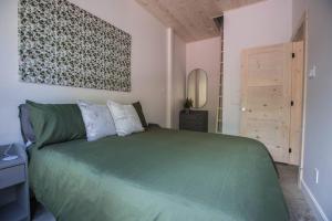 a bedroom with a green bed and a mirror at Le Boréal in Saint-Donat-de-Montcalm