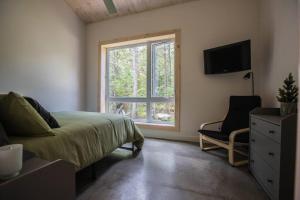 a bedroom with a bed and a window and a chair at Le Boréal in Saint-Donat-de-Montcalm