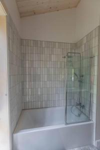 a bath tub with a glass shower in a bathroom at Le Boréal in Saint-Donat-de-Montcalm