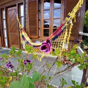 a hammock in front of a house with purple flowers at Chalés Alto do Capivari in Campos do Jordão