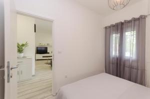 a white bedroom with a bed and a television at Apartment Maja with Jacuzzi in Rupe
