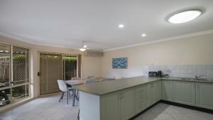 a kitchen with a counter and a table and chairs at Banksia Villa Umina Beach in Umina