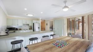 a kitchen with a wooden table and some chairs at Banksia Villa Umina Beach in Umina