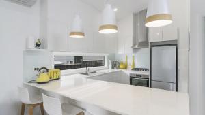 une cuisine blanche avec un grand comptoir blanc dans l'établissement Beach St Cottage - Ettalong, à Ettalong Beach