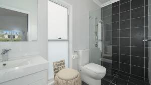 une salle de bain avec toilettes, lavabo et miroir dans l'établissement Beach St Cottage - Ettalong, à Ettalong Beach