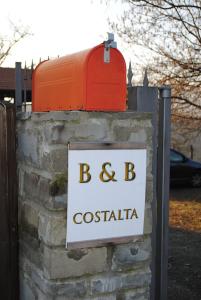 a sign on a brick wall with a red mailbox at B&B Costalta in Compiano