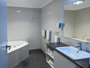 y baño con lavabo, bañera y espejo. en Arkana Motor Inn & Terrace Apartments en Mount Gambier