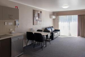 salon ze stołem, krzesłami i kanapą w obiekcie Arkana Motor Inn & Terrace Apartments w mieście Mount Gambier