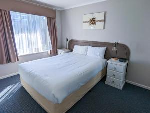 Un dormitorio con una cama grande y una ventana en Arkana Motor Inn & Terrace Apartments, en Mount Gambier