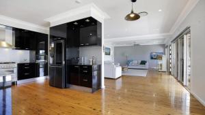 a kitchen with black cabinets and a living room at Bayview Escape Woy Woy Bay in Woy Woy