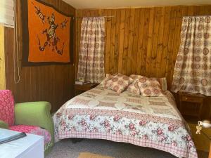 a bedroom with a bed and a chair and curtains at Cabaña del bosque con estero in Curiñanco