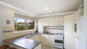 a kitchen with white cabinets and a large window at Vietta Rene Umina Beach in Umina