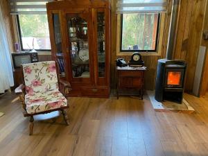a living room with a chair and a wood stove at Cabaña del bosque con estero in Curiñanco