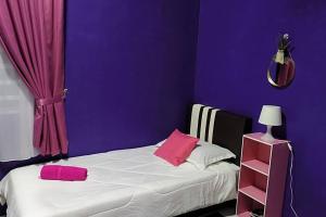 a purple bedroom with a bed with two pink pillows at CASA Singgah Homestay in Chemor