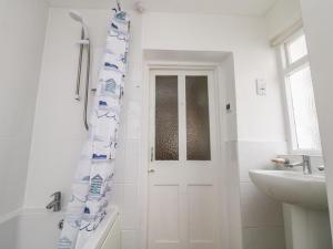 a bathroom with a shower and a white door at Calac Cottage in Mousehole +26 photos