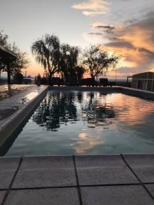 a swimming pool with a sunset in the background at Complejo Puesta del Sol san Luis in La Punta