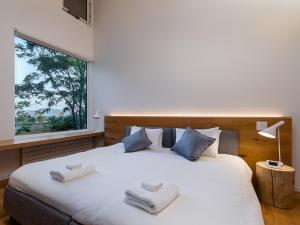 a bedroom with a large white bed with towels on it at Yukihyo by H2 Life in Niseko