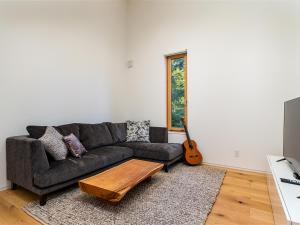 a living room with a couch and a guitar at Yukihyo by H2 Life in Niseko