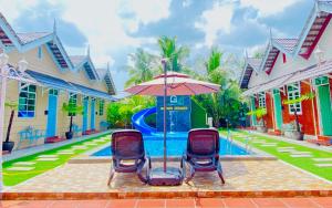 a pool with two chairs and an umbrella at Gading Chalet in Kuala Terengganu