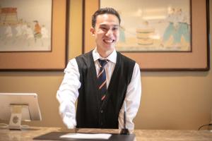 a man in a vest and tie sitting at a desk at Furuya Ryokan in Atami
