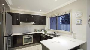 a kitchen with a sink and a refrigerator and a window at Ocean Beach Holiday House in Ettalong Beach