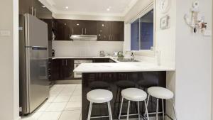 a kitchen with a island with bar stools and a refrigerator at Ocean Beach Holiday House in Ettalong Beach