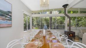 Casa Bianca - Pearl Beach في بيرل بيتش: غرفة طعام مع طاولة طويلة وكراسي بيضاء