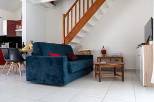 ein Wohnzimmer mit einem blauen Sofa und einem Tisch in der Unterkunft La Villa Noémie - Parking - Proche des Plages in Sainte-Anne