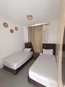 Mini villa dakhla في دخلة: سريرين في غرفة بجدران بيضاء
