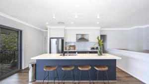 a kitchen with a blue island with three stools at Bay Edge - Tascott in Point Clare