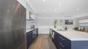 a kitchen with blue cabinets and a white counter top at Bay Edge - Tascott in Point Clare
