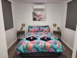 AAOK Lakes Resort and Caravan Park في Berry Springs: غرفة نوم مع سرير مع لحاف ملون