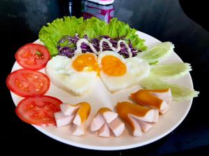 talerz jajek i sałatki z pomidorami i sałatą w obiekcie Kangaroo Residence Udonthani w mieście Udon Thani