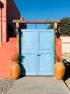 deux grands vases assis devant une porte bleue dans l'établissement WAYTAY, à Cafayate