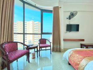 Habitación de hotel con cama, sillas y ventana en Hai Dang Hotel en Cửa Lò