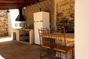 a kitchen with a refrigerator and a table with chairs at Solar dos Tios in São Thomé das Letras