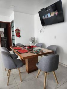 einen Esstisch mit Stühlen und einen TV an der Wand in der Unterkunft Elegante, hermoso y equipado in Villeta