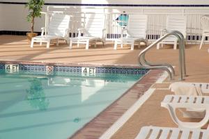 einen Pool mit weißen Stühlen und einem Schwimmpooliterator in der Unterkunft Watson's Regency Suites in Ocean City