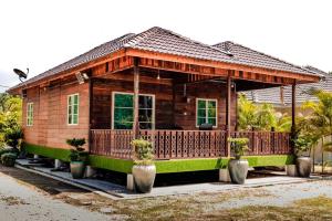 een klein houten huis met een veranda en potplanten bij As Sufi Villa 