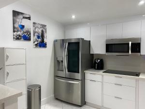 a kitchen with white cabinets and a stainless steel refrigerator at Beautiful House 7 min from Miami Airport w FREE parking in Miami